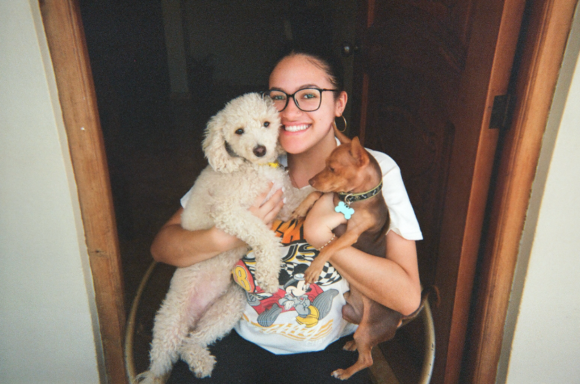 Yaritza sitting down with dogs, smiling for the camera.